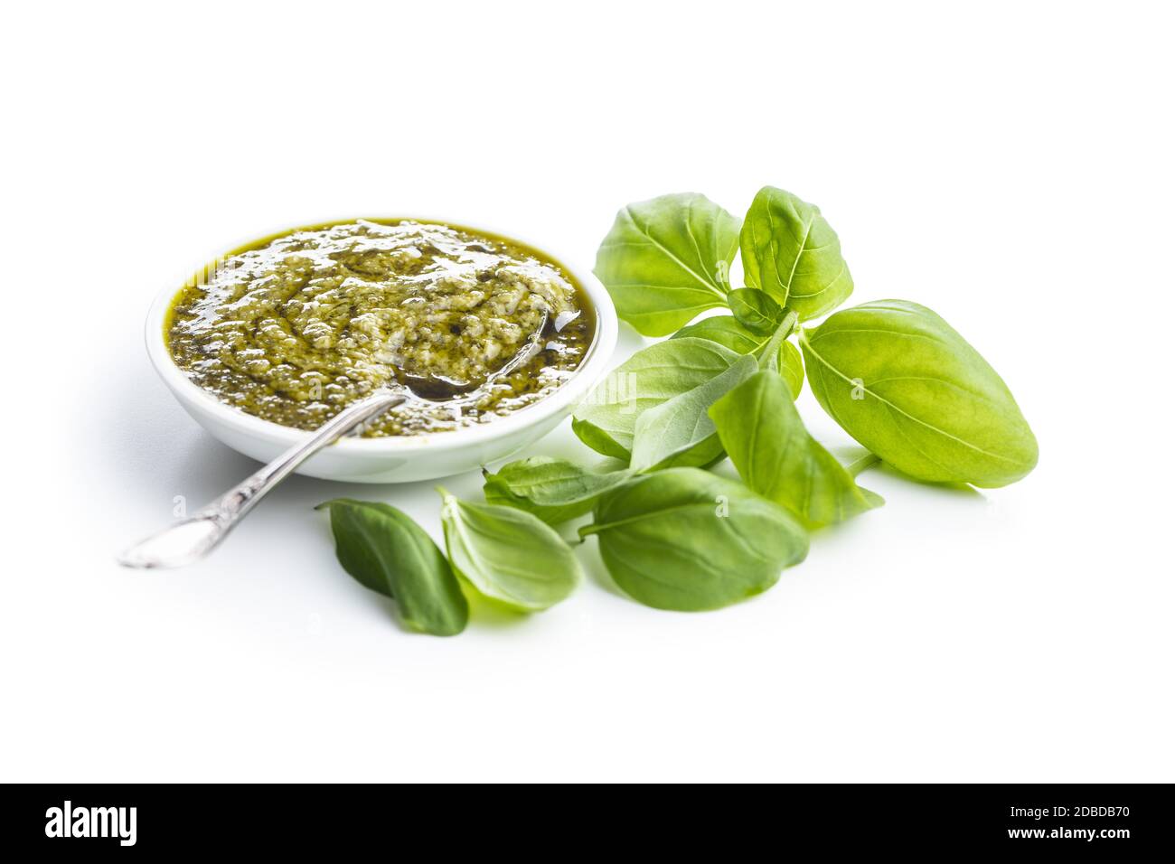 Green basil pesto dip sauce and basil leaves isolated on white
