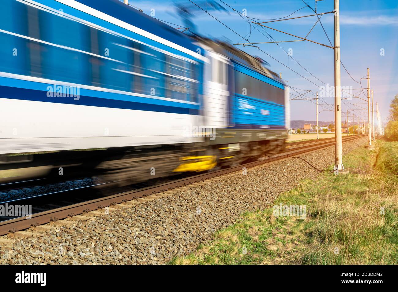 train going to a stop opposite the sun. Stock Photo