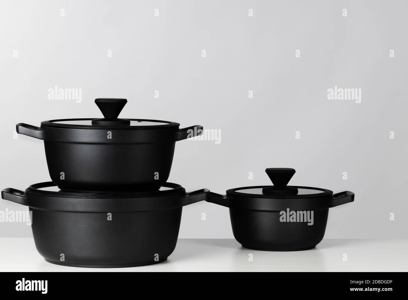 Black cooking pots on grey background front view Stock Photo Alamy
