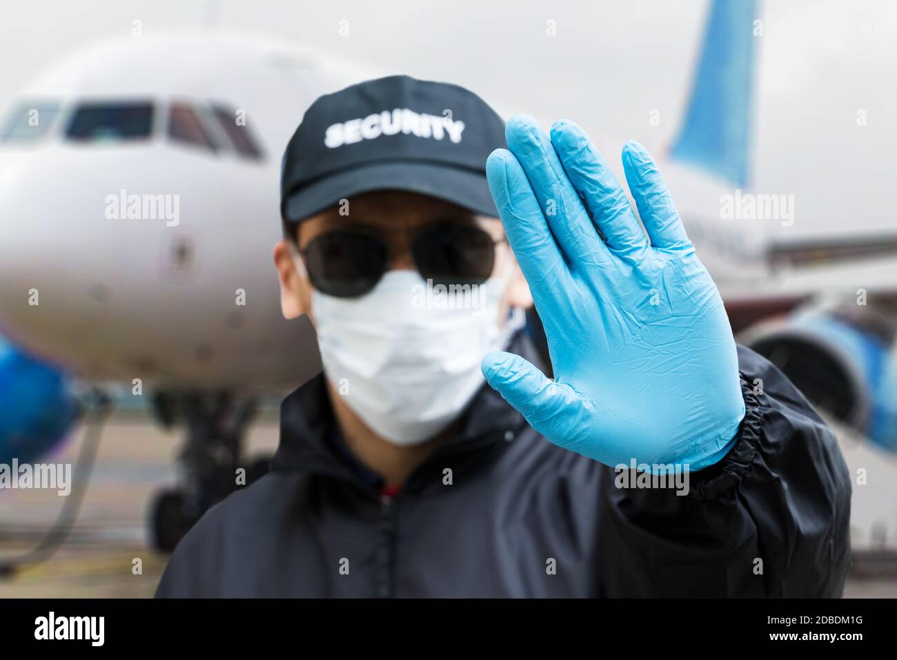 Security Guard Making Stop Gesture Near Airplane Stock Photo