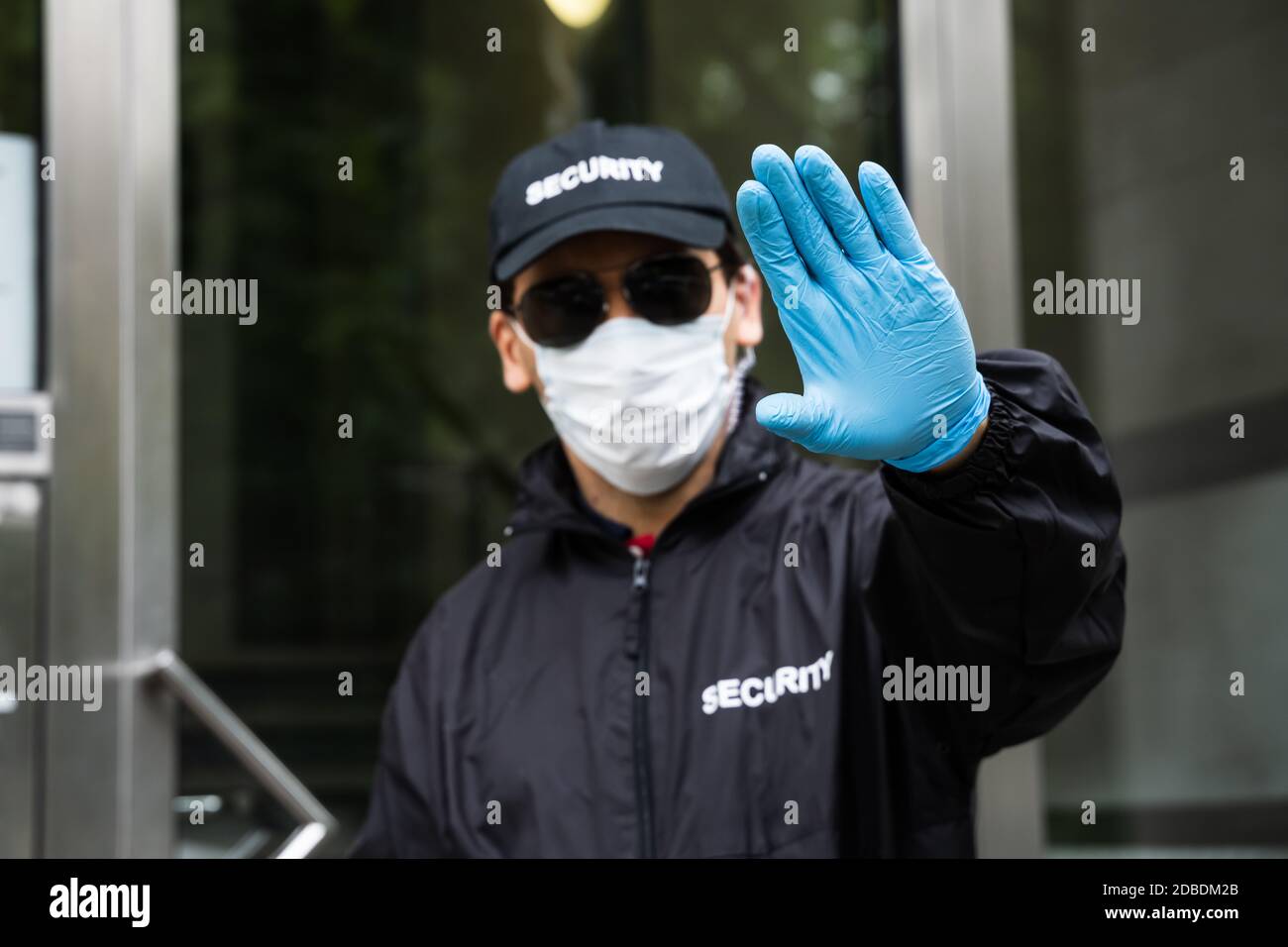 Security Guard In Uniform And Face Mask Making Stop Hand Gesture Stock Photo