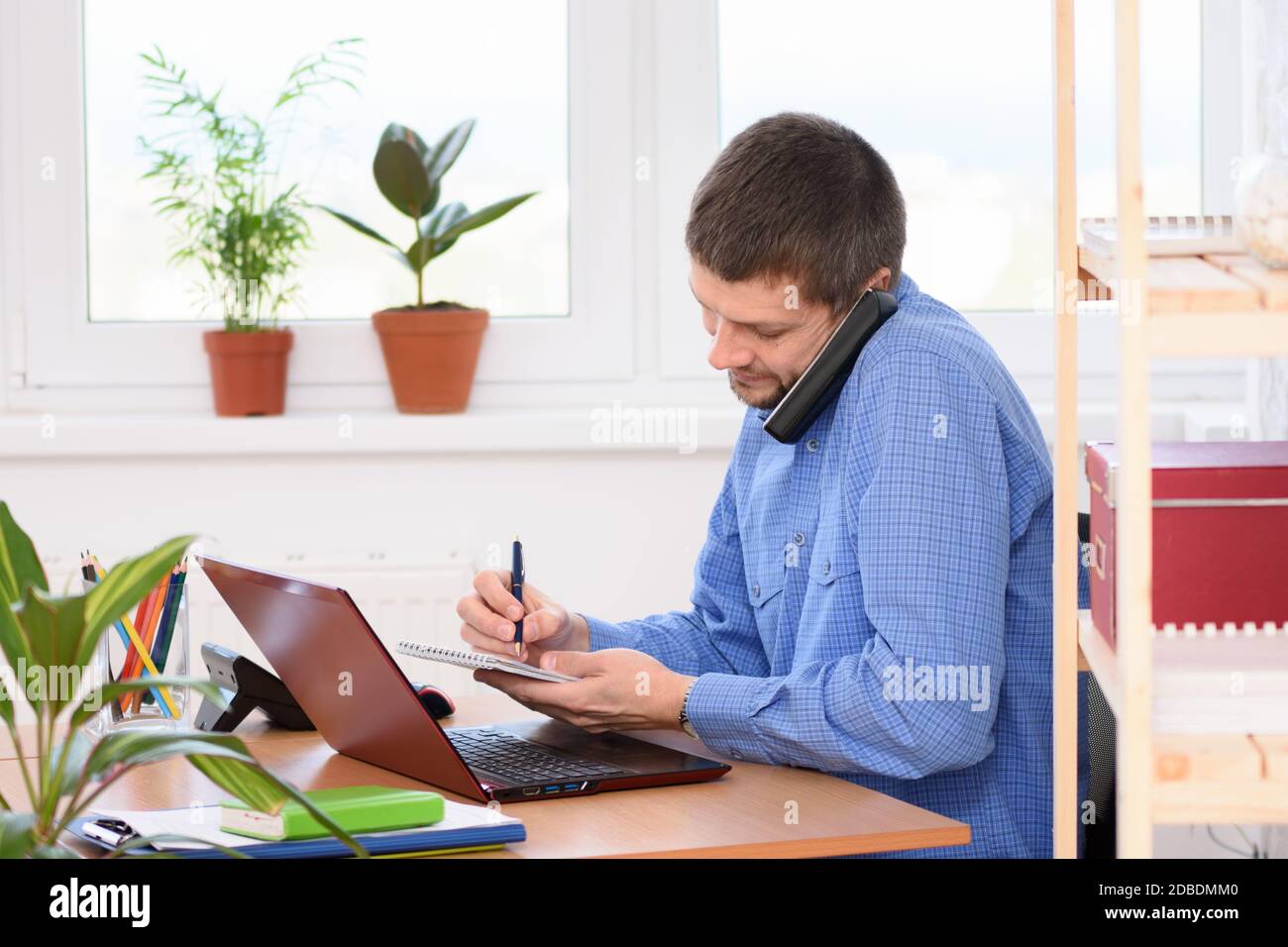 Businessman talking on the phone and taking notes in a notebook Stock Photo
