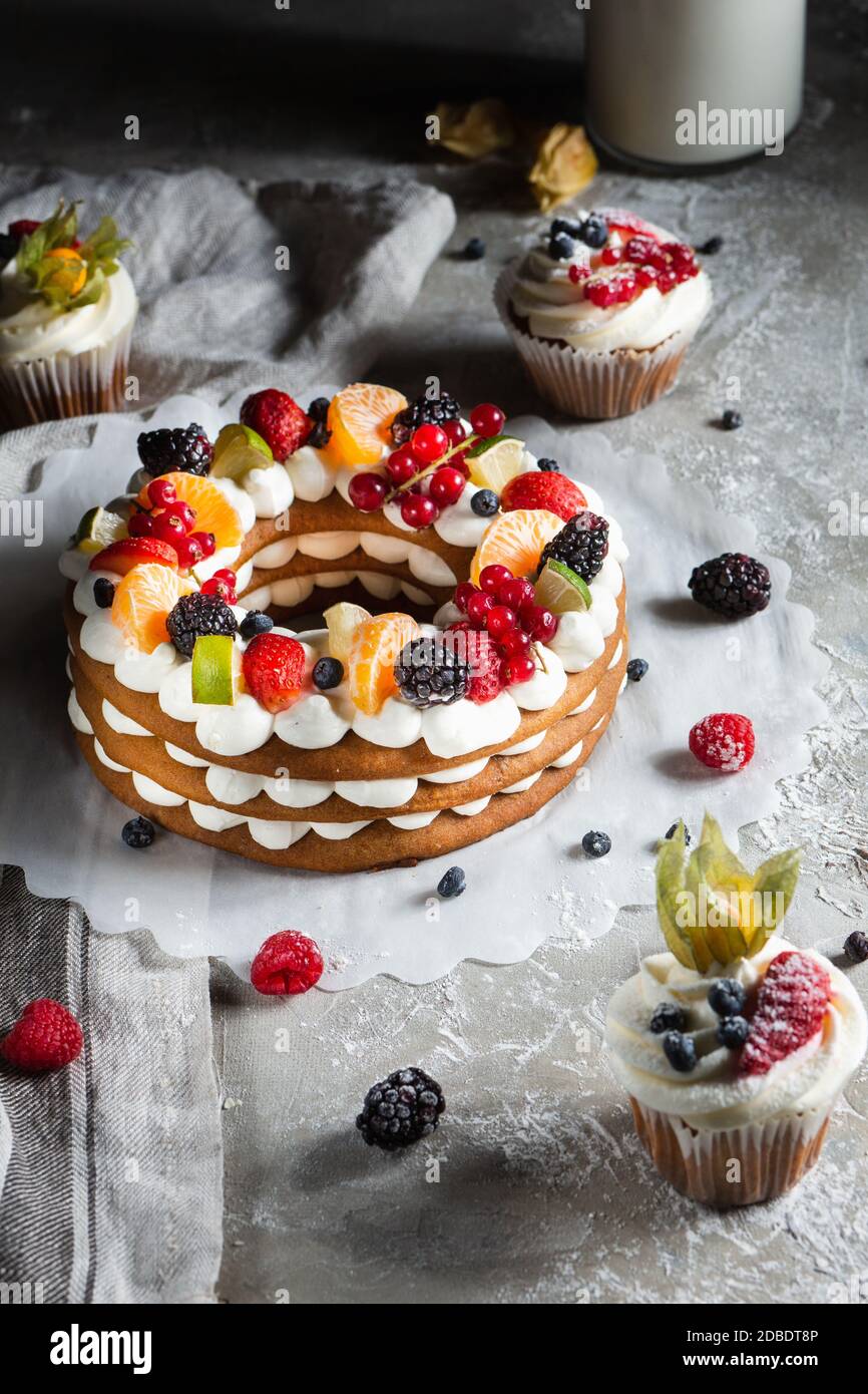 round pie with berries and cupcake on a gray background Stock Photo