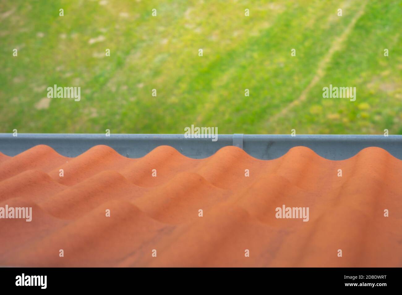 roof tiles and gutter view from above from the roof. brown roof tiles. rain gutter on the roof and view of green meadow Stock Photo