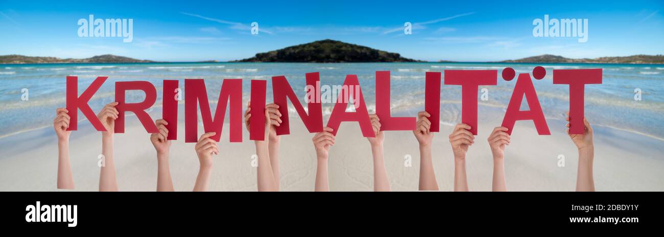 People Hands Holding Colorful German Word Kriminalitaet Means Crime. Ocean And Beach As Background Stock Photo