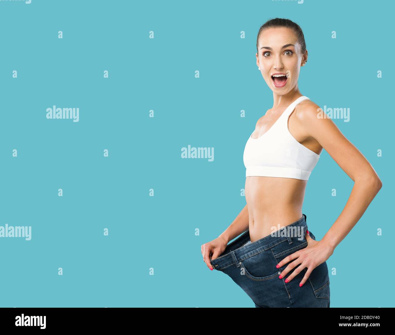 Happy woman showing her successful weight loss, her jeans are loose and she is slim, weight loss and fitness concept Stock Photo