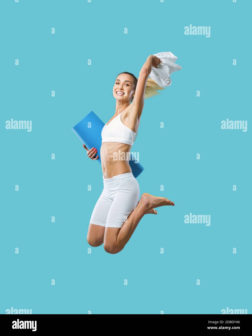 Cheerful slim woman working out and jumping, she is holding a mat, healthy lifestyle and weight loss concept Stock Photo