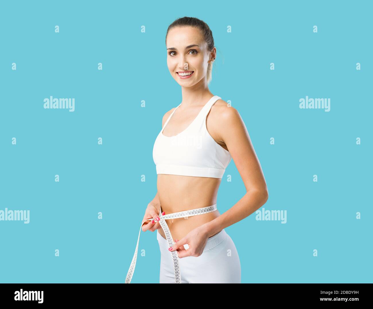 Young fit woman measuring her waist using a measuring tape, weight loss and fitness concept Stock Photo