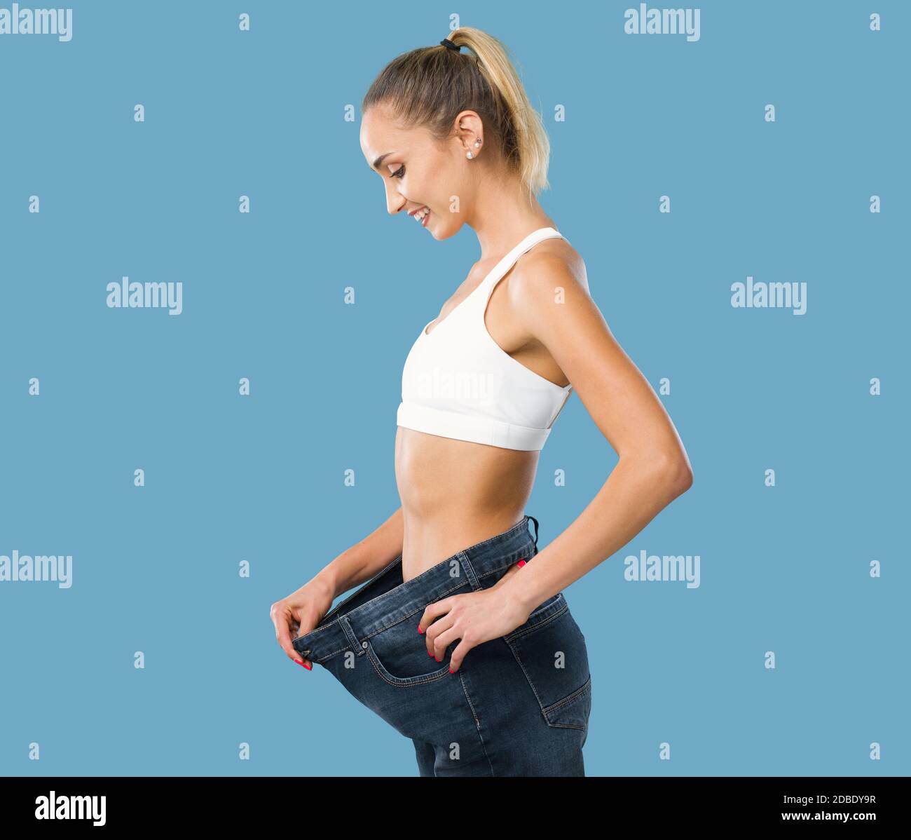 Woman showing her successful weight loss, her jeans are loose and she is slim, weight loss and fitness concept Stock Photo