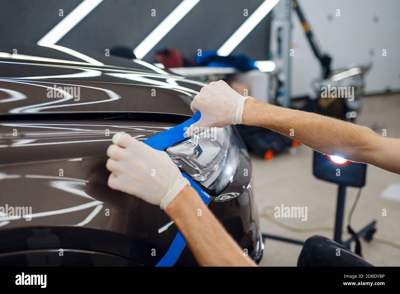 Male worker prepares car surface to applying of protection film