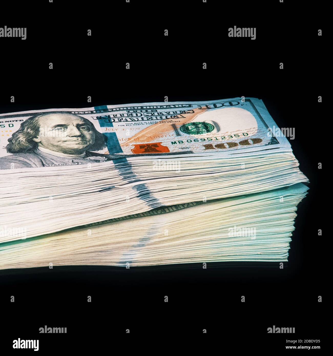 Isolated bundle of dollars. A large stack of hundred-dollar bills lies on a black background in the center of the image with a reflection. A color ful Stock Photo