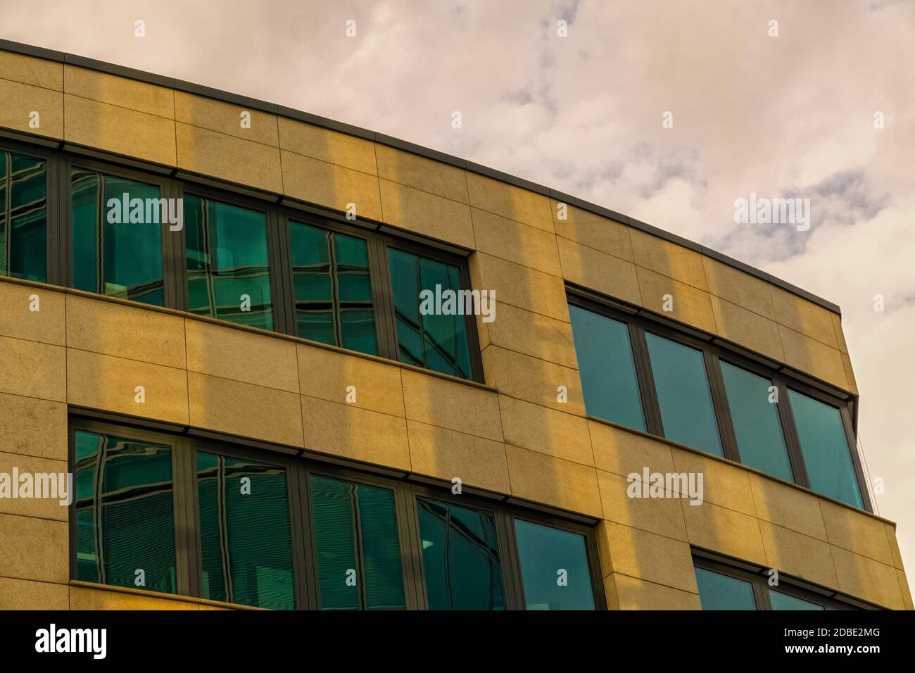 A modern office building below a cloudy sky Stock Photo - Alamy