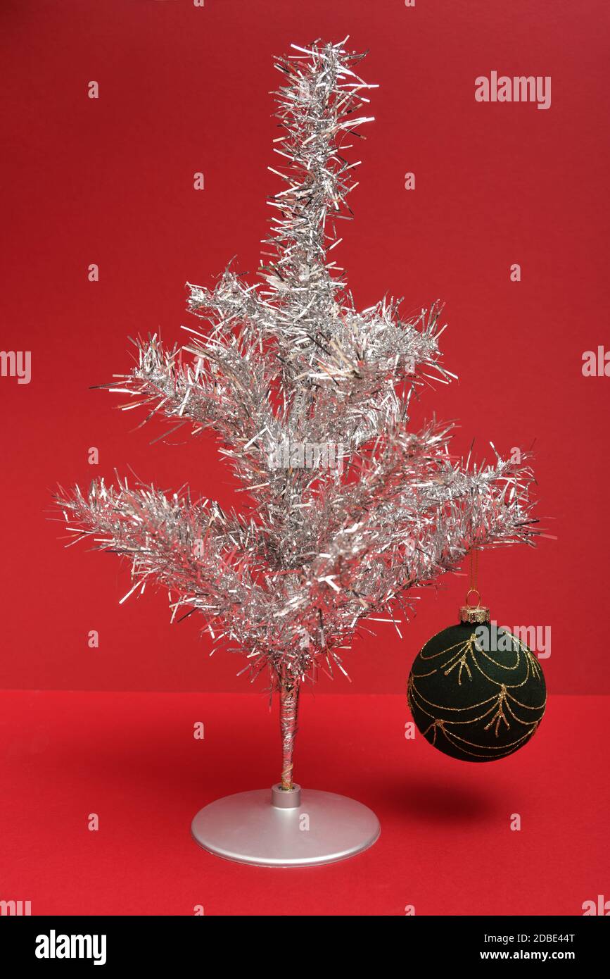 Retro silver tinsel Christmas tree with bauble on a red background Stock Photo