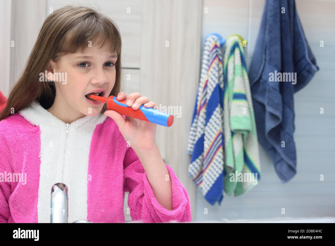 Ten year old girl brushes her teeth with an electric toothbrush in the bathroom Stock Photo Alamy