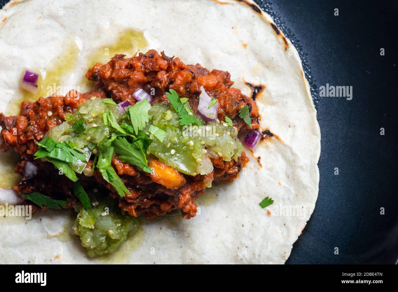 Vegetarian, vegan tacos al pastor with green salsa. Soya protein cooked with al pastor marinade and served on corn tortillas. Stock Photo