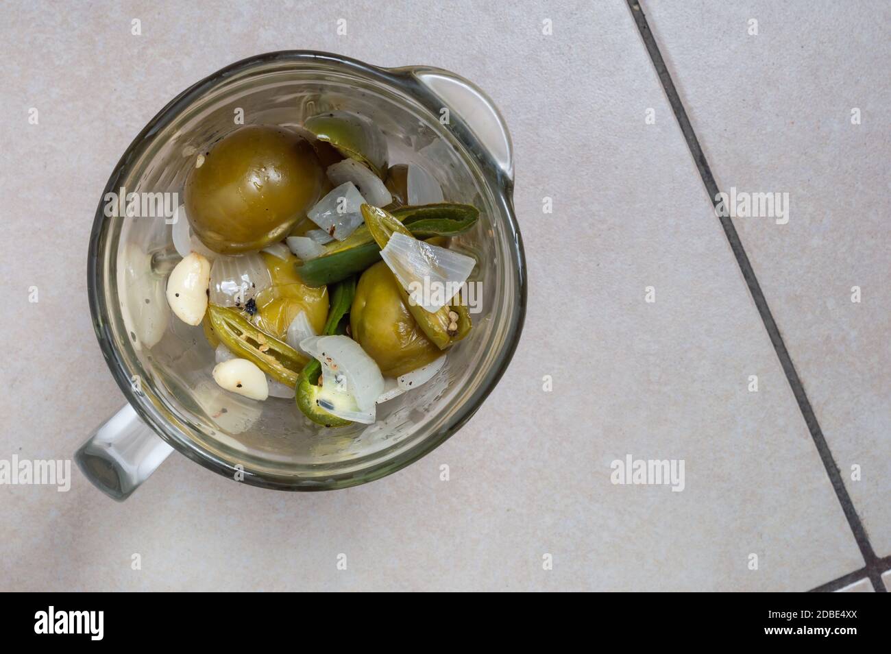 Making Mexican green tomatillo and chili salsa, Mexican food. Ingerdient in blender jar, sauce in blender jar Stock Photo