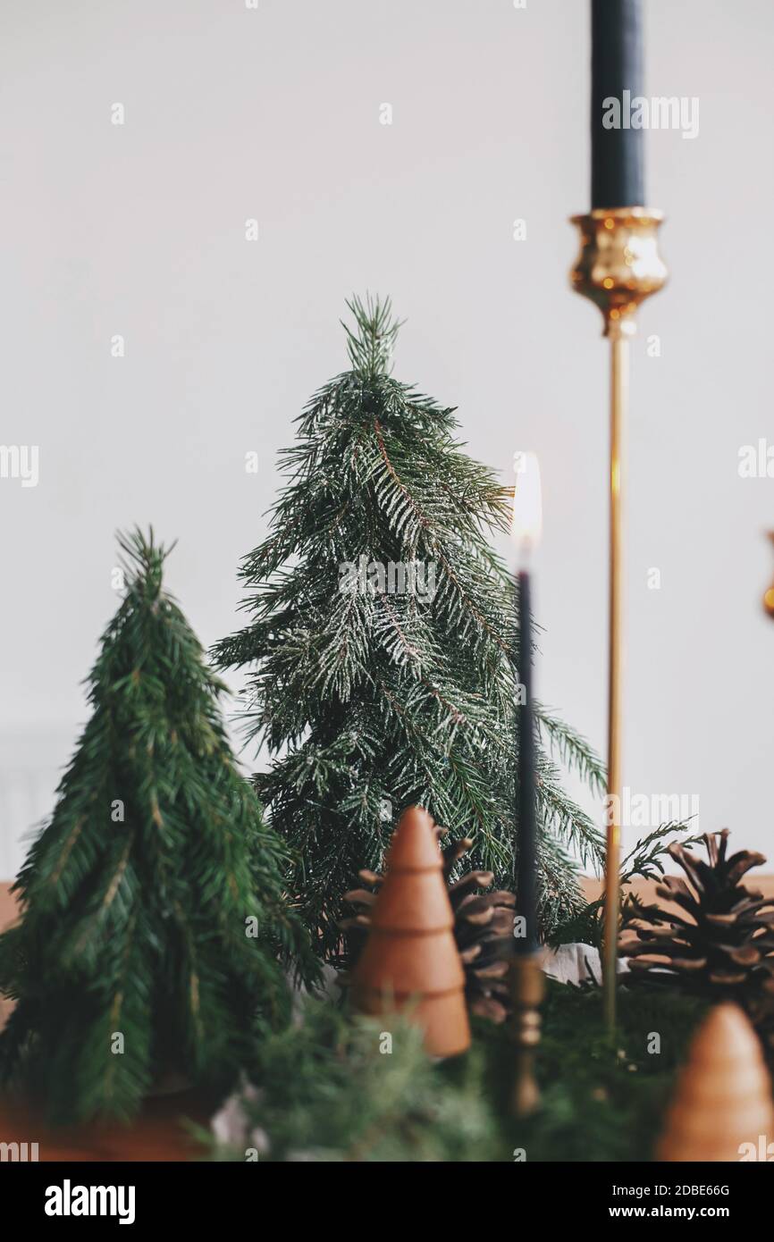 Christmas trees, candles and pine cones on linen on rustic wooden table ...
