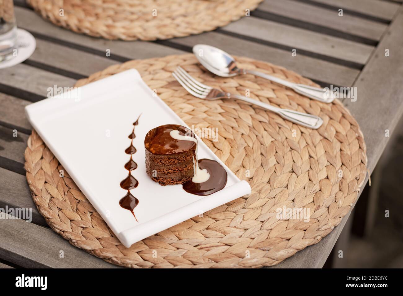 Chocolate fondant cake with cream on a white dish, part of a dessert serving in a restaurant Stock Photo