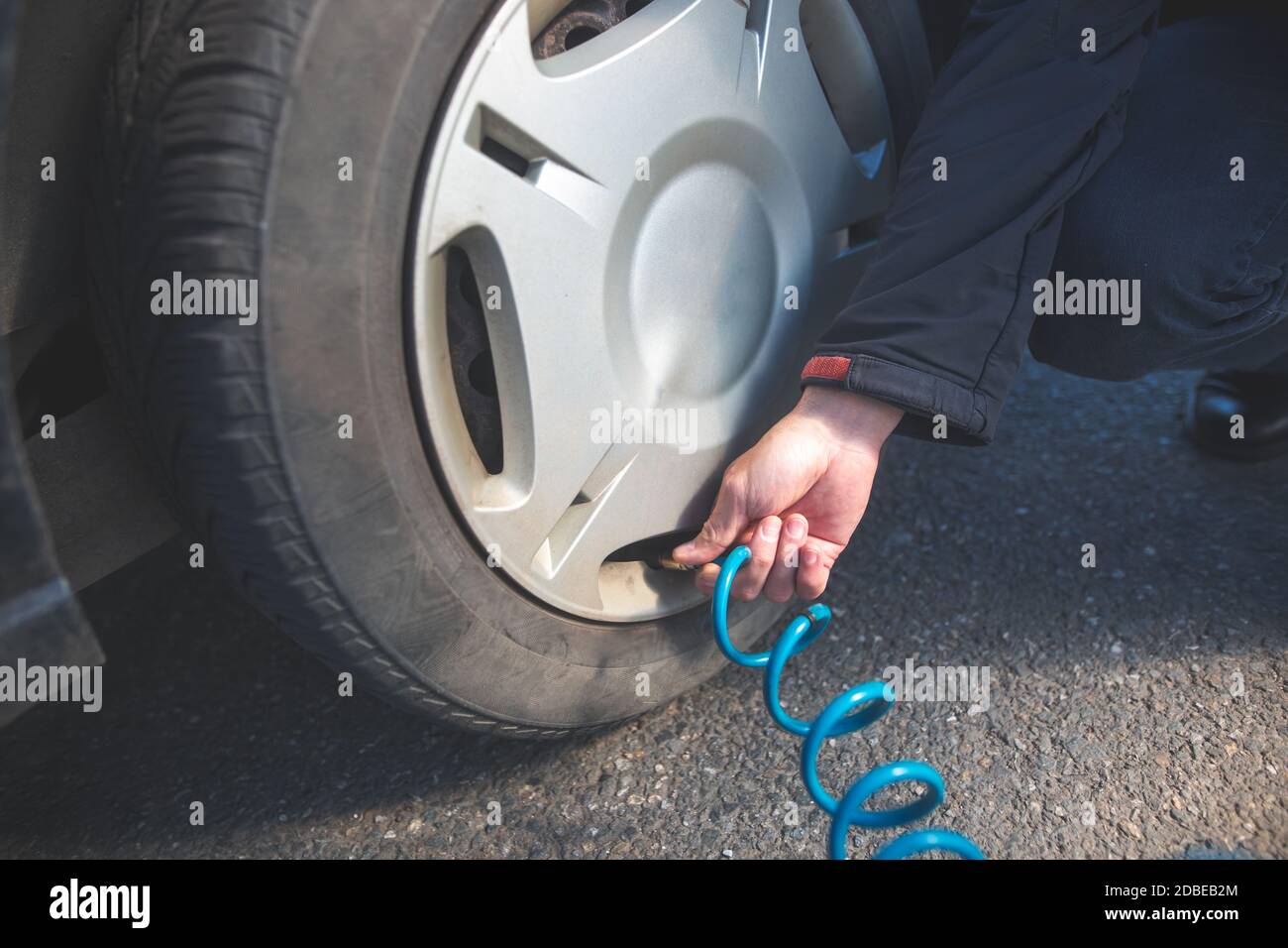 Man driver checking air pressure and filling air in the tires of his