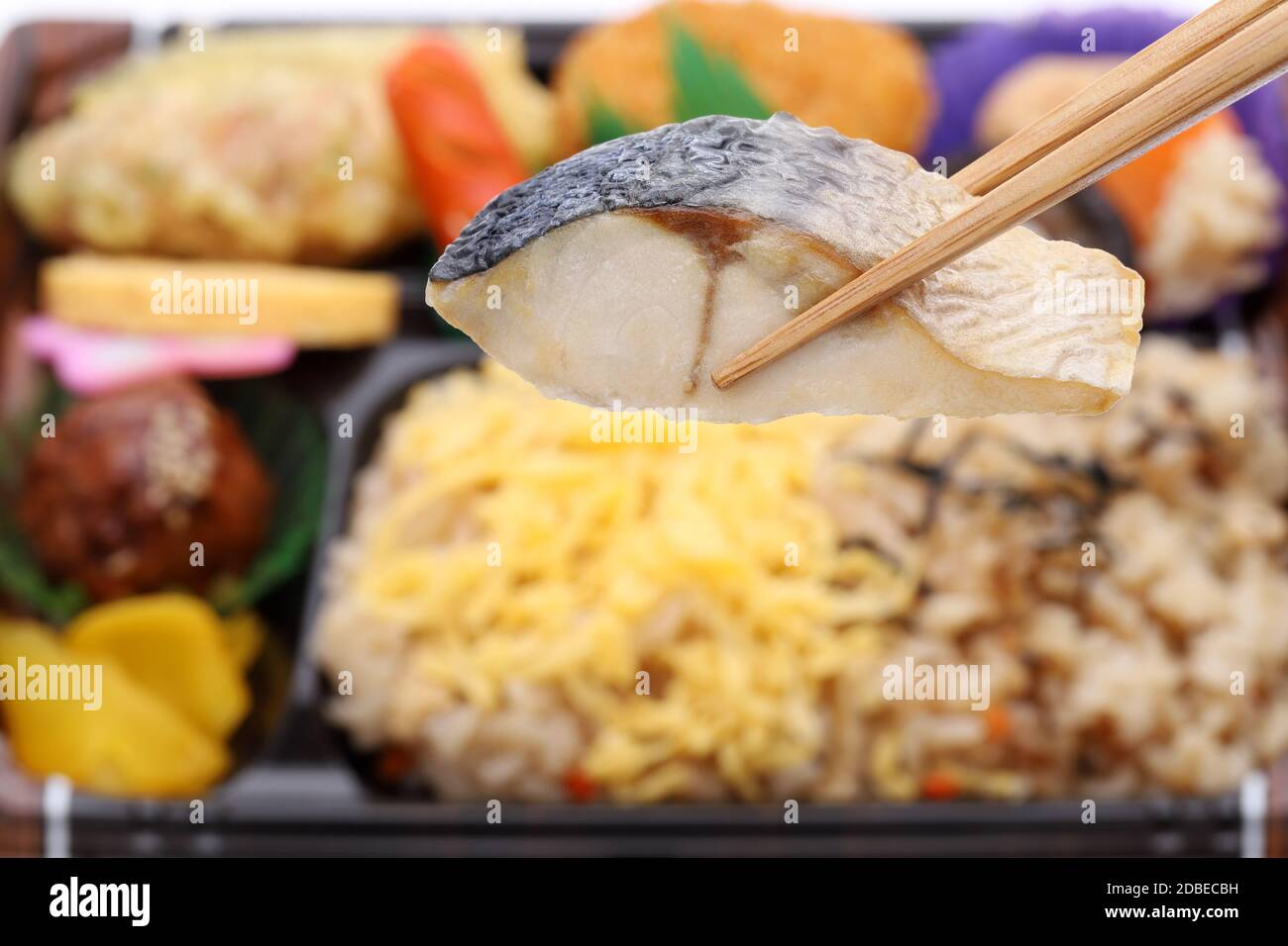 Japanese bento lunch background, grilled fish held with chopstick, close up Stock Photo