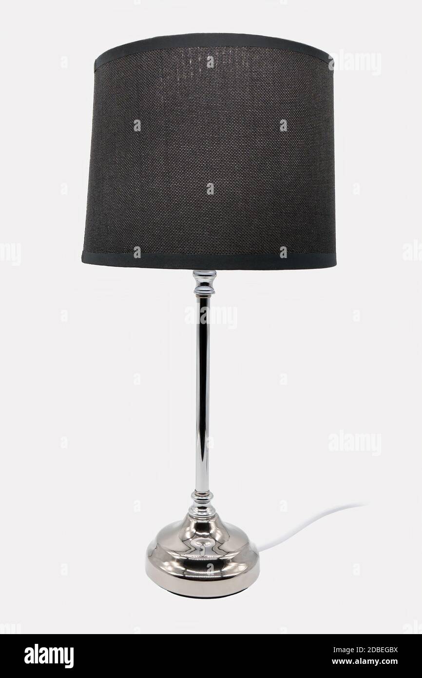A modern floor lamp with a black lampshade and chrome-colored base Stock Photo