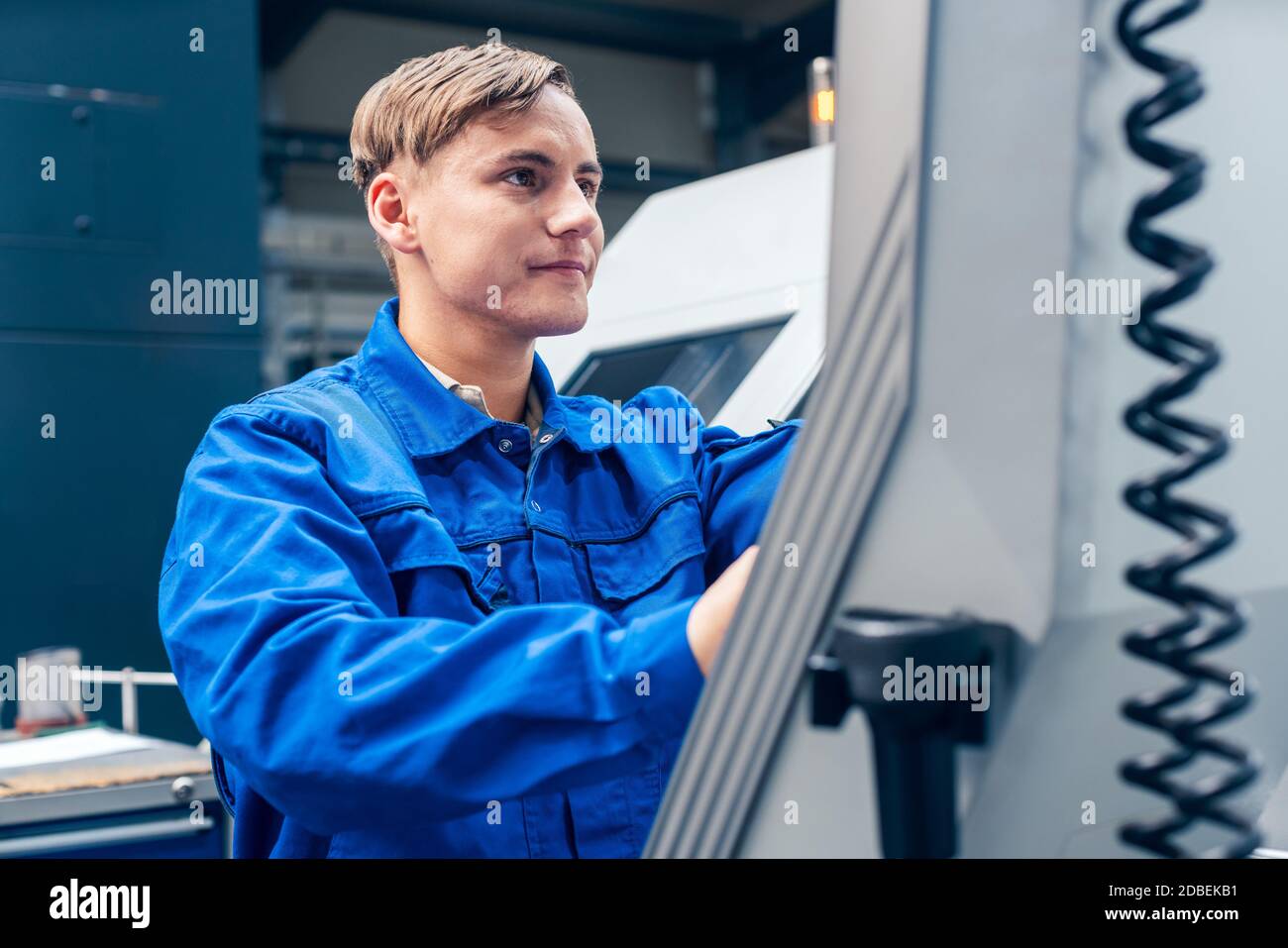 Young male worker programming lathe machine in factory Stock Photo