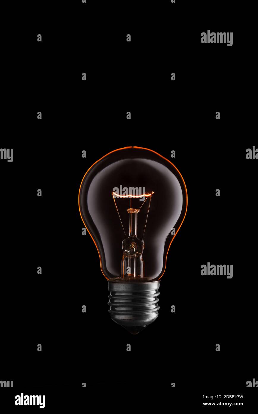 Burning Light bulb on black background. Stock Photo