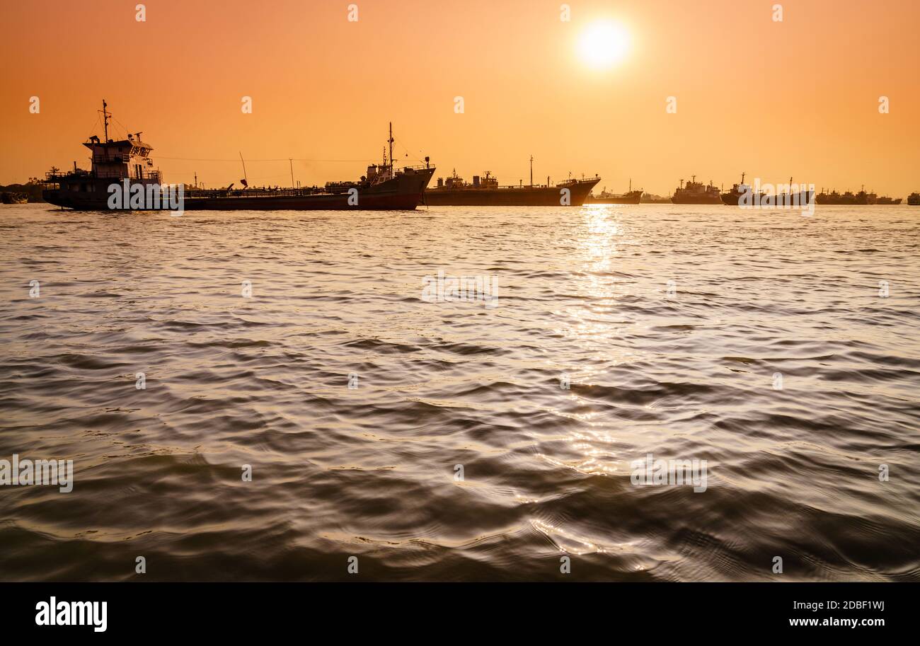 Commercial ships on anchorage in the Karnaphuli River in Bangladesh at sunset Stock Photo