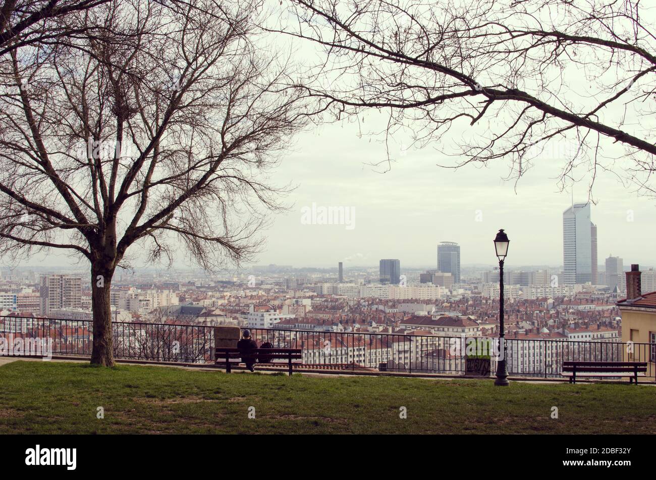 A man sitting and staring at Lyon, from the Pentes de la Croix Rousse, a winter morning Stock Photo