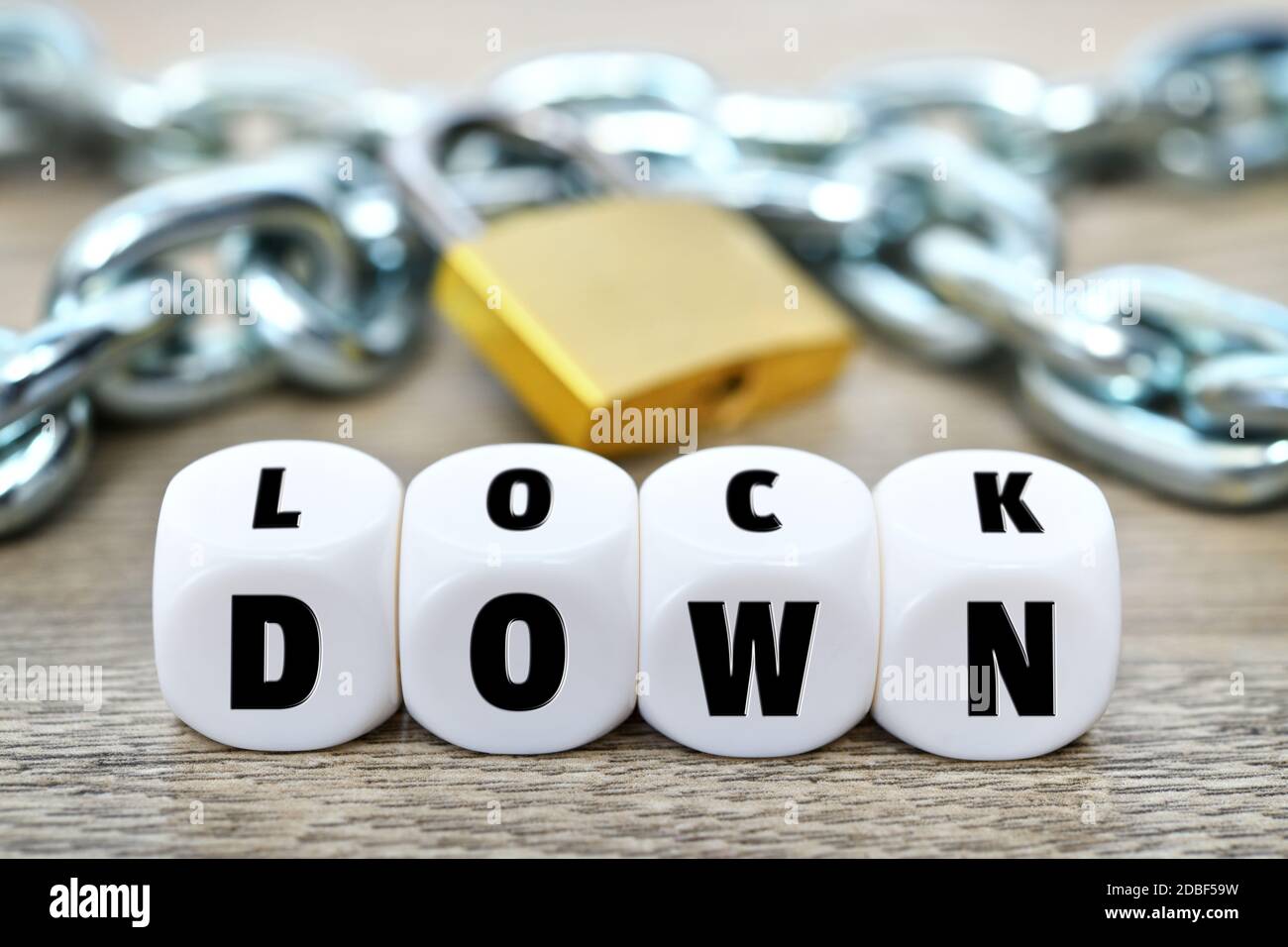 Letter cubes forming the word lockdown in front of iron chain and padlock, corona lockdown Stock Photo