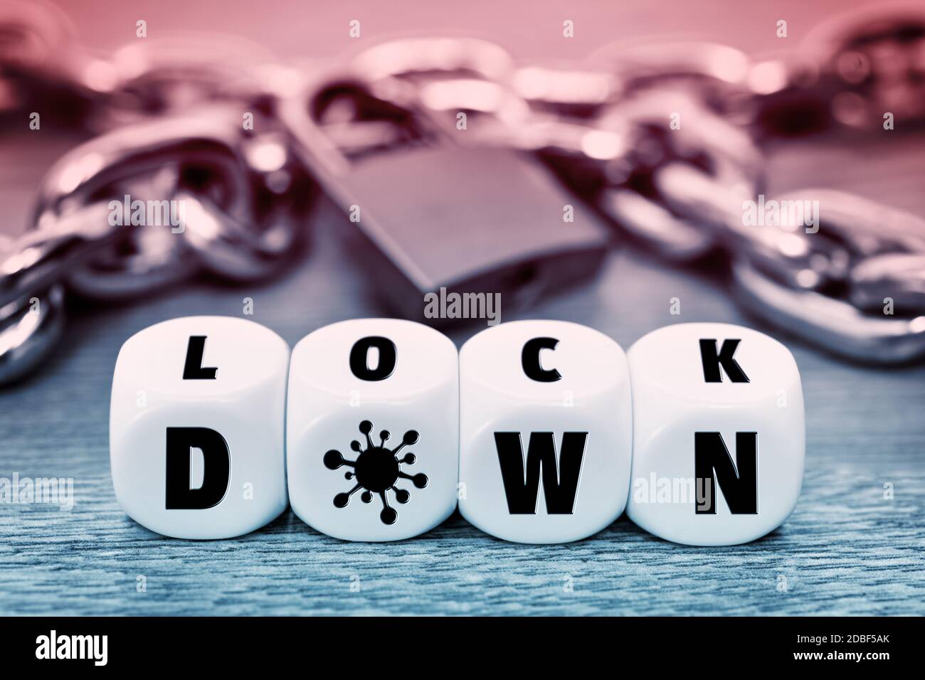 Letter cubes forming the word lockdown in front of iron chain and padlock, corona lockdown Stock Photo