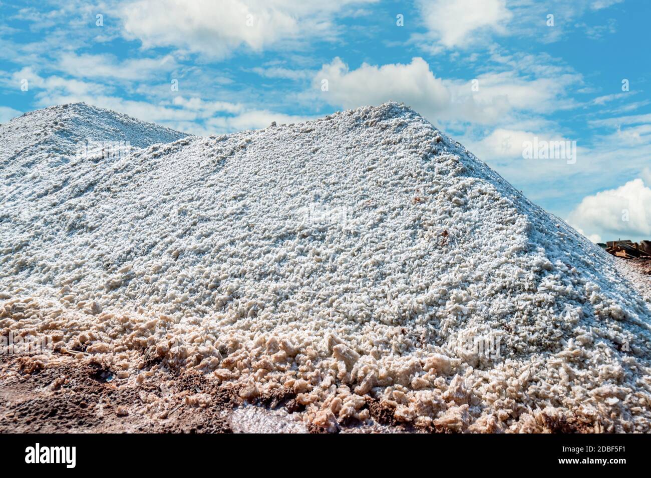 Brine salt farm with blue sky and white clouds. Pile of organic sea