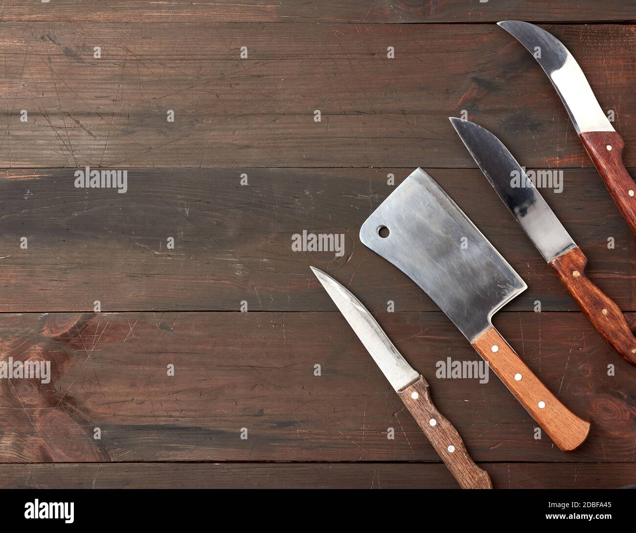 set of different kitchen knives with wooden handles on a brown