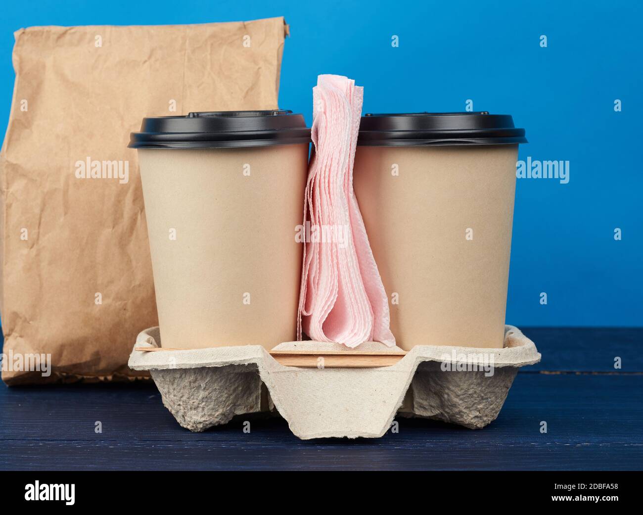 https://c8.alamy.com/comp/2DBFA58/brown-paper-disposable-cups-with-a-plastic-lid-stand-in-the-tray-on-a-blue-wooden-table-takeaway-containers-2DBFA58.jpg