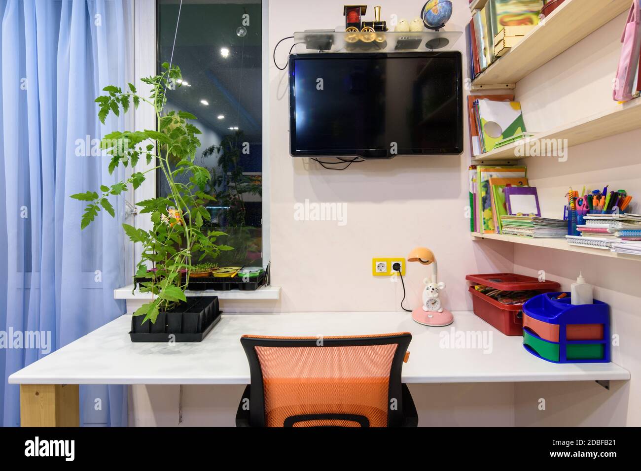 A desk in the children's room, on the wall a TV and shelves for school books Stock Photo