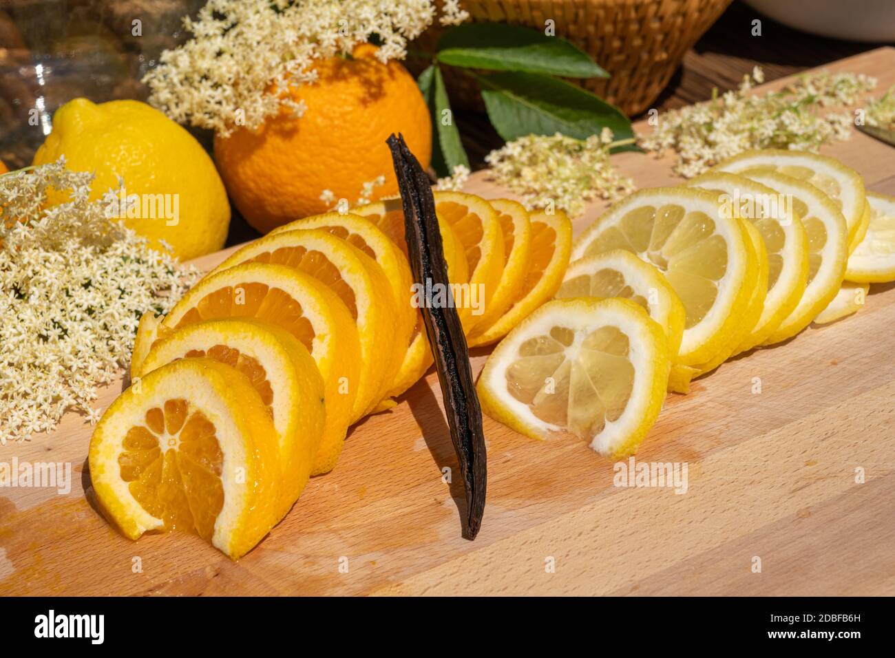 On a cutting board lie a sliced organic lemon and organic orange and a vanilla pod for the elderflower liqueur Stock Photo