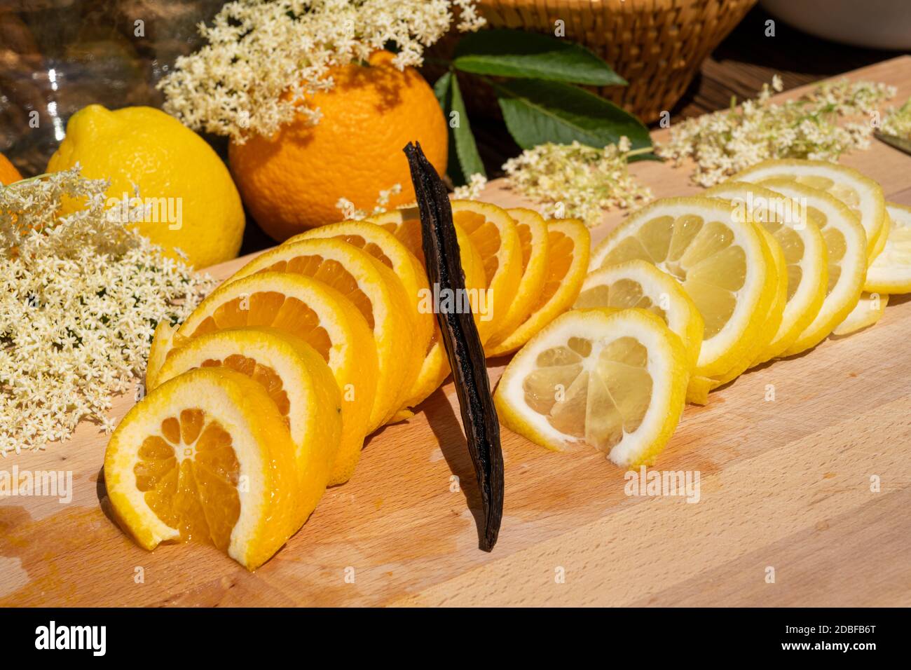 On a cutting board lie a sliced organic lemon and organic orange and a vanilla pod for the elderflower liqueur Stock Photo