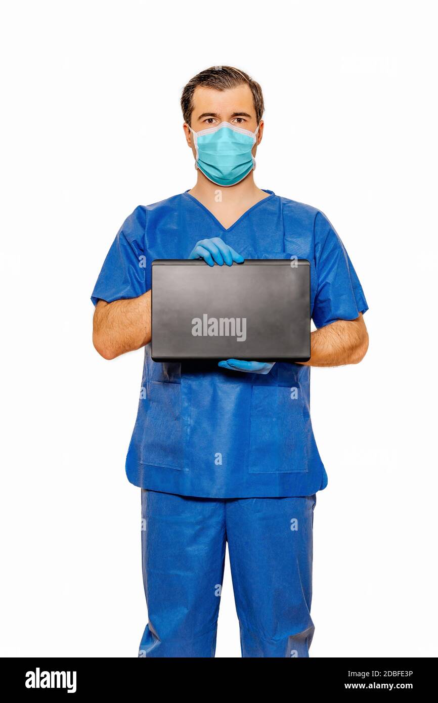 Male doctor in scrubs with protective face mask holding tablet with space for your text and creative ideas. Plain white background Coronavirus concept Stock Photo