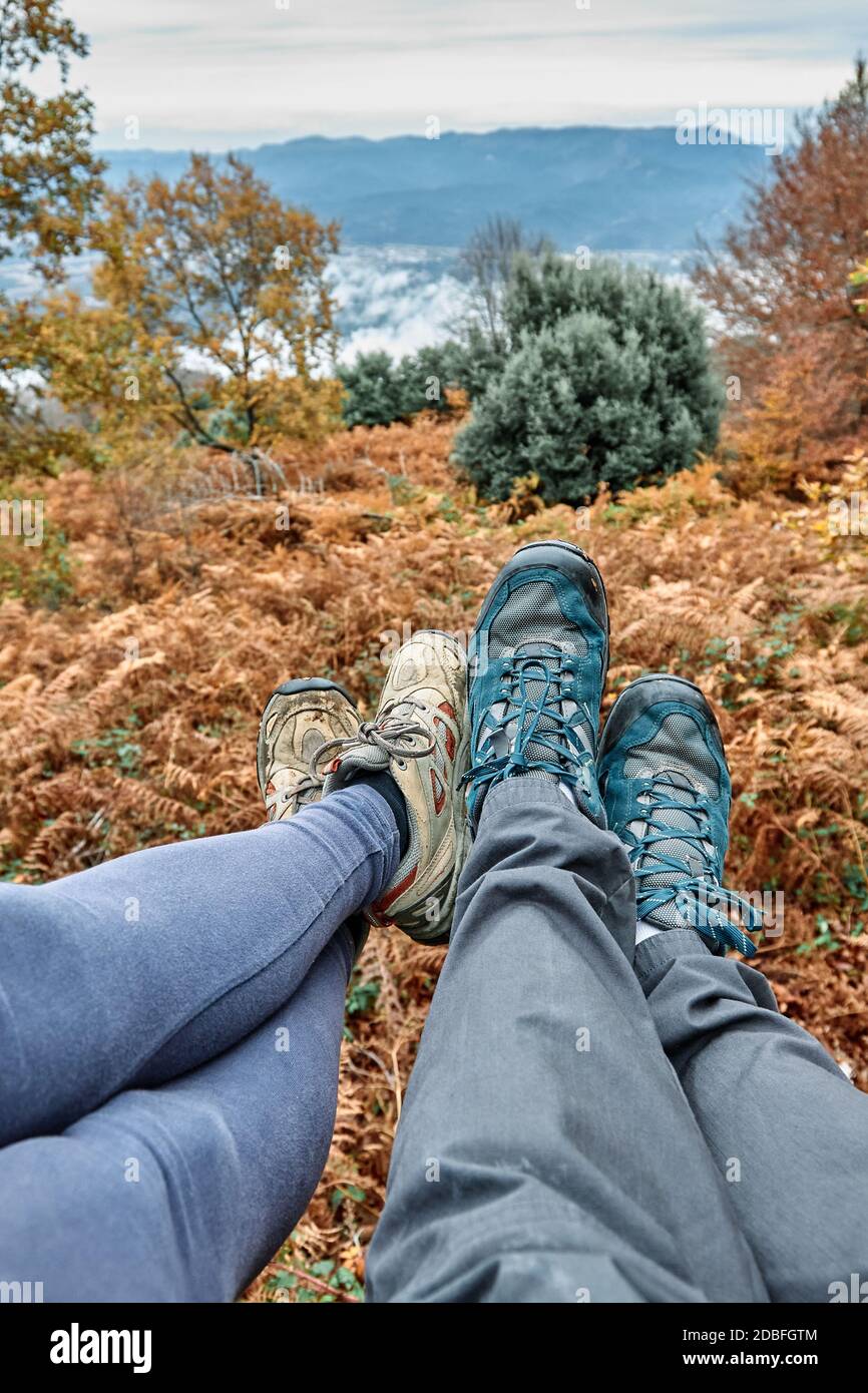 Couple sitting in the forest, only the feet and shoes are visible. Unrecognizable persons. Stock Photo