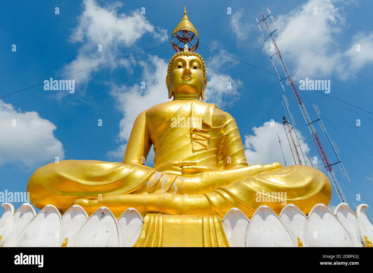 Monumental Buddha figure, gilded, with head umbrella, on top of Tiger rock near Krabi Thailand, and radion antenna in background. Stock Photo