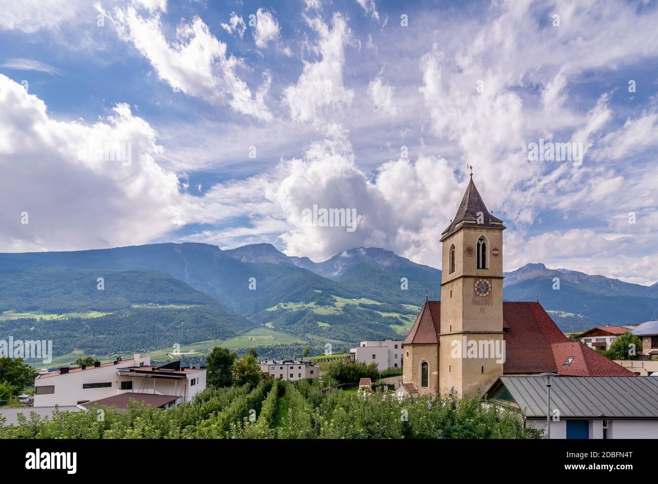 The parish church Pfarrkirche St. Johannes der Täufer in Corzes, South Tyrol, Italy, against a dramatic sky Stock Photo