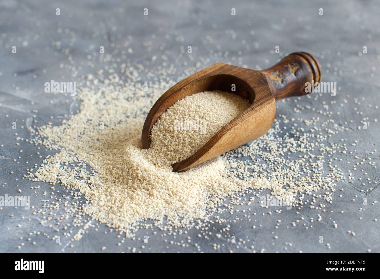 Raw uncooked fonio seeds with a spoon on grey background close up Stock Photo