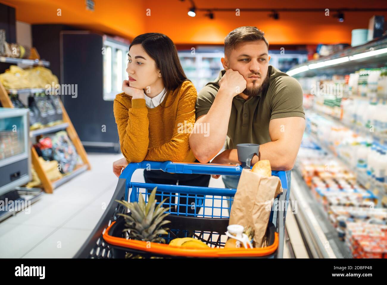 https://c8.alamy.com/comp/2DBFP4B/bored-family-couple-in-grocery-store-man-and-woman-with-cart-buying-beverages-and-products-in-market-two-customers-shopping-food-and-drinks-2DBFP4B.jpg