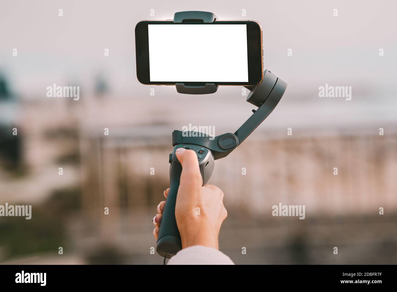 Woman hand with a gimbal for smartphone with blank screen. Vlog and video blogging concept. Stock Photo