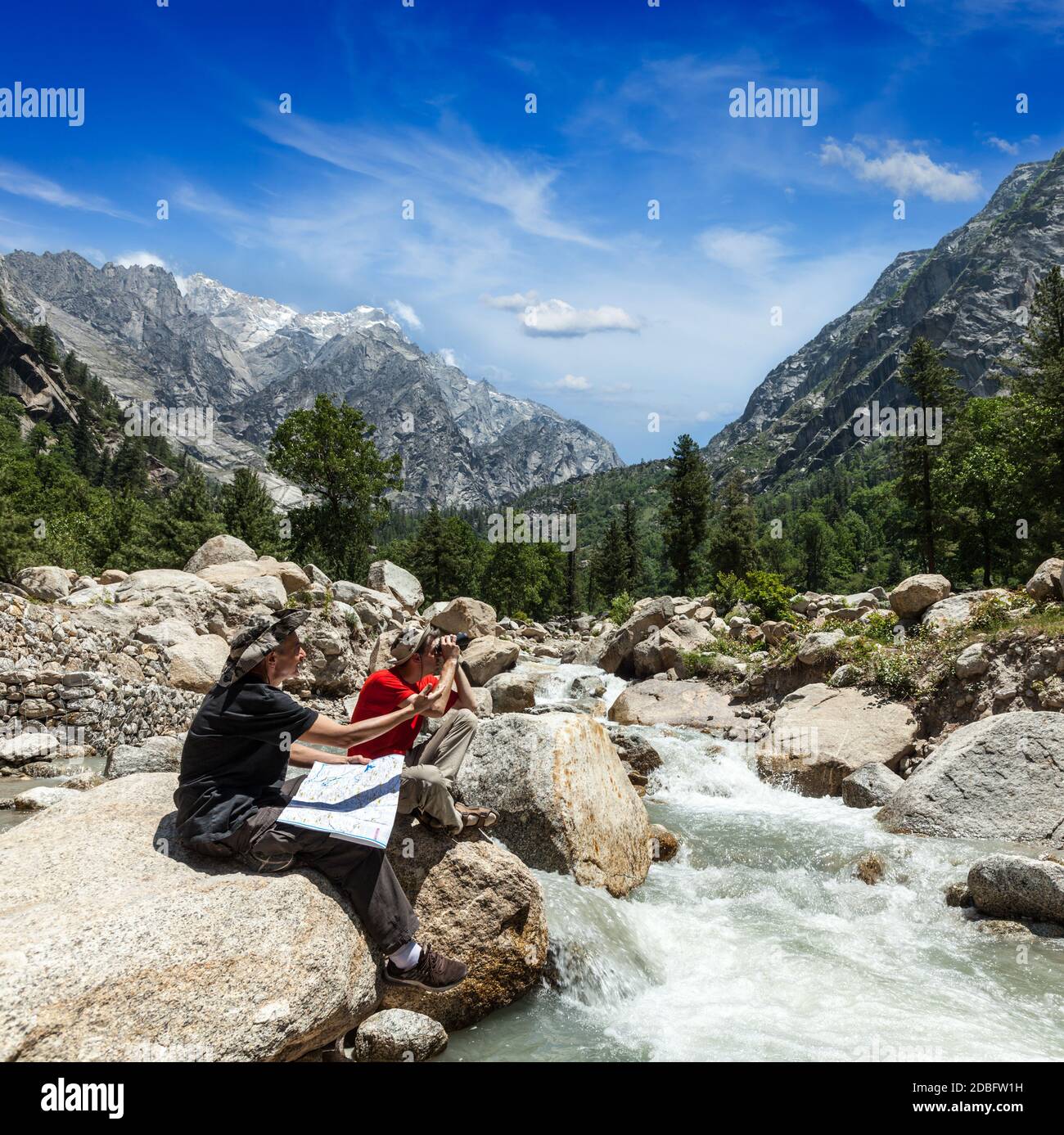 Hiker trekkers read a trekking map on trek in Himalayas mountains. Himachal Pradesh,India Stock Photo