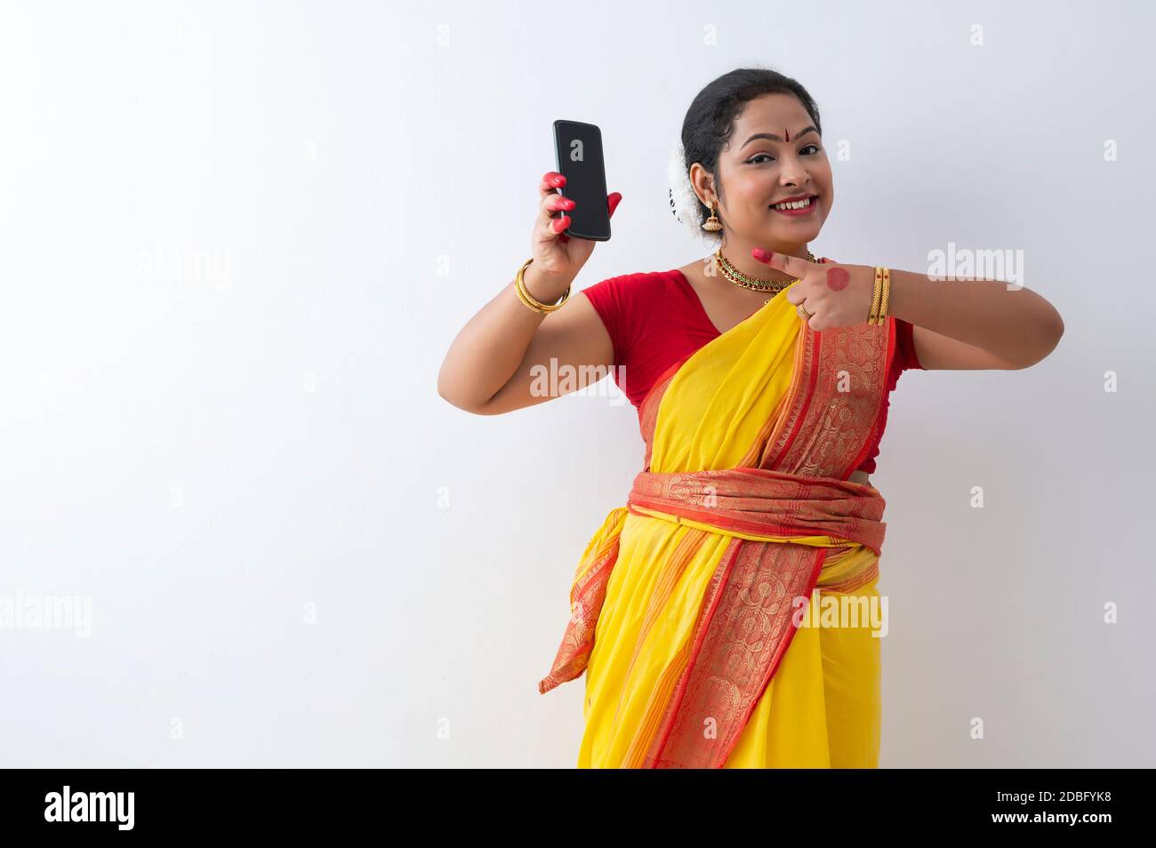 Kuchipudi dancer pointing towards the phone in her hand with a smile Stock Photo