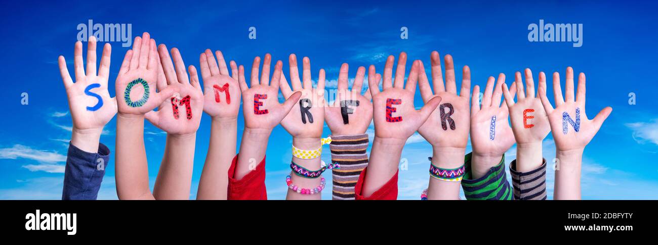 Children Hands Building Colorful German Word Sommerferien Means Summer Holdiays. Blue Sky As Background Stock Photo