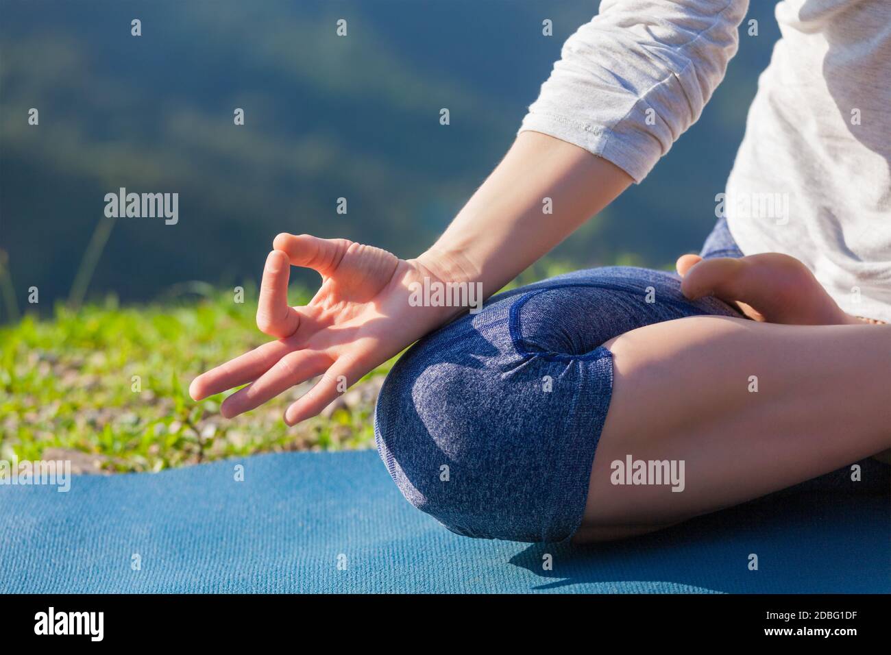 Meditation relaxation concept background - close up of woman in Padmasana yoga lotus pose with chin mudra outdoors with copyspace Stock Photo