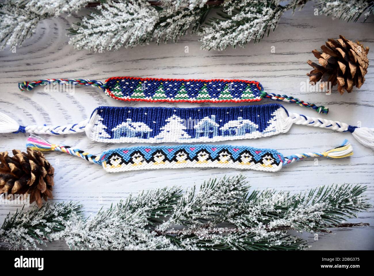 Woven friendship bracelets with alpha patterns Snowy night with  houses,penguins, fir trees. Handmade of thread, on wooden background with  spruce cones Stock Photo - Alamy