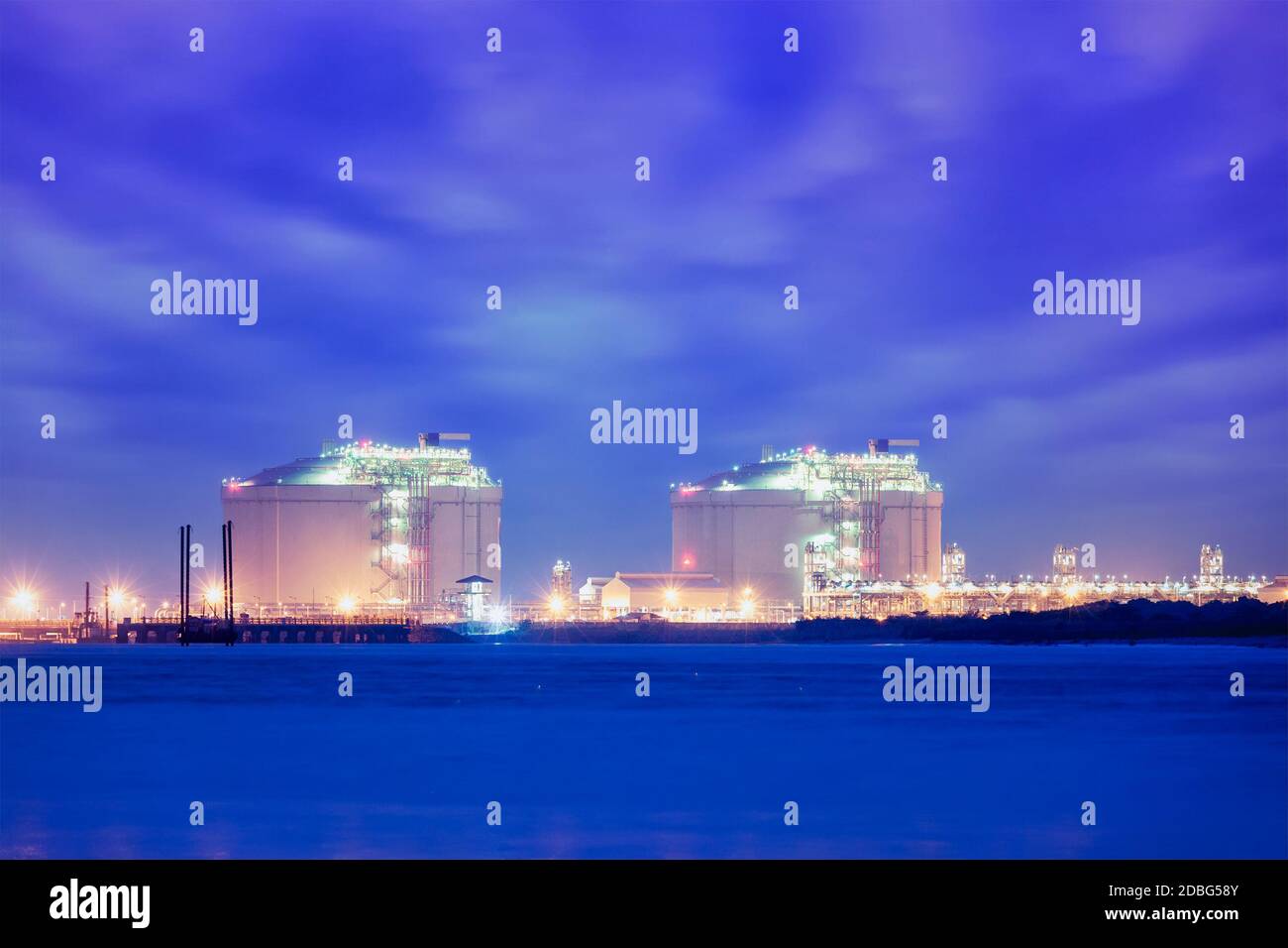 Industrial liquified natural gas (LNG) reservoir tanks in sea port in twilight Stock Photo